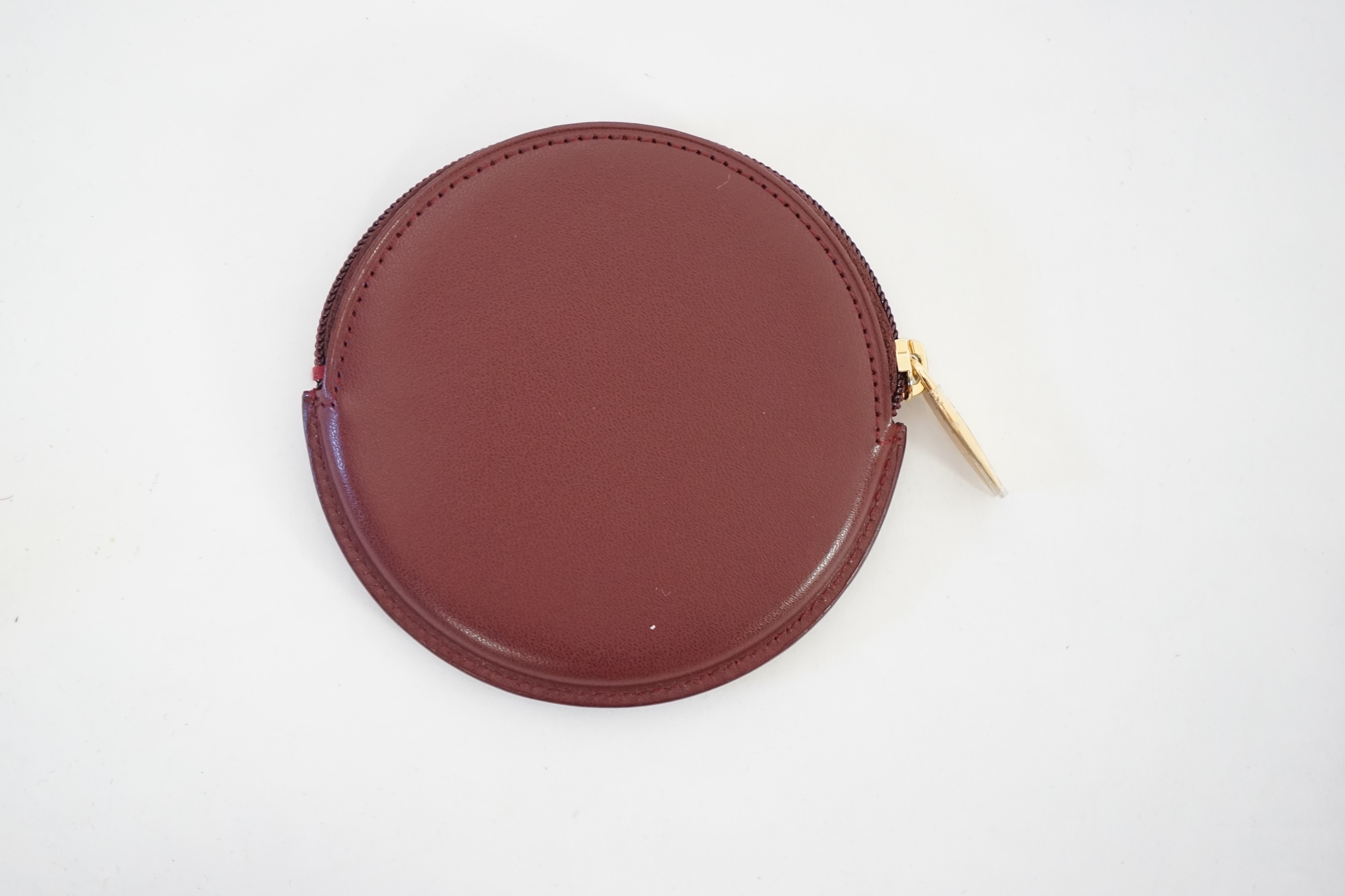 A Cartier maroon leather circular purse with box.